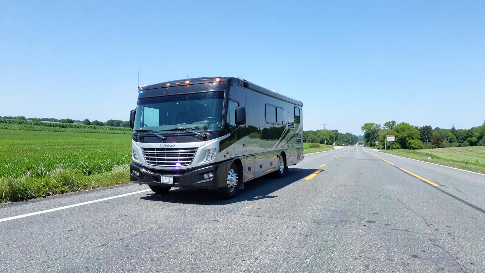 Motorhome stopped on the shoulder of a rural Pennsylvania highway beside green farm fields
